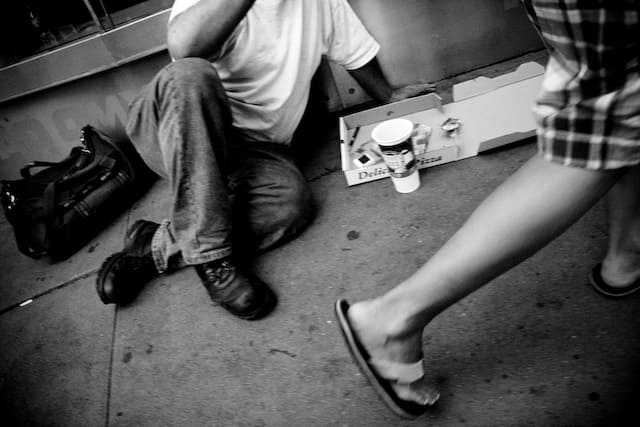 Man eating pizza on the streets while people passing by (picture taken with Canon EOS 40D and Canon EF 16-35mm F2.8 L USM)