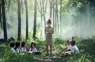 An asian teacher is educating her students in the forest