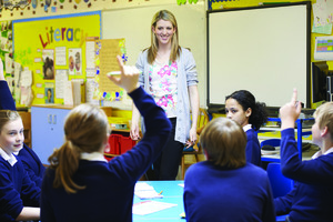 Teaching in front of her class and students are raising their hands